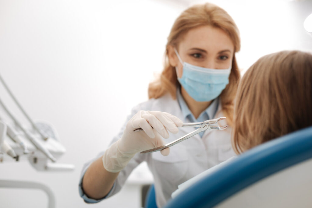 Dentystka w trakcie zabiegu ekstrakcji zęba - jak dbać o dziąsła po usunięciu zęba