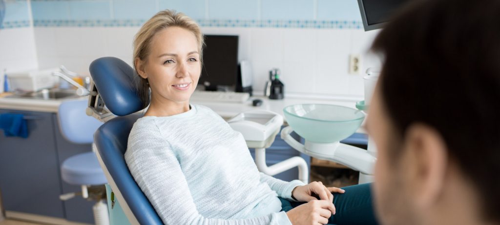 Kobieta rozmawia z dentystą. O co warto zapytać dentystę podczas wizy