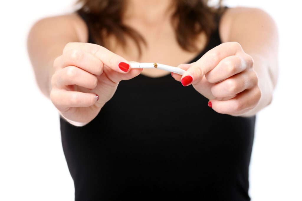 Młoda kobieta łamie papierosa - Krwawienie z dziąseł a palenie papierosów