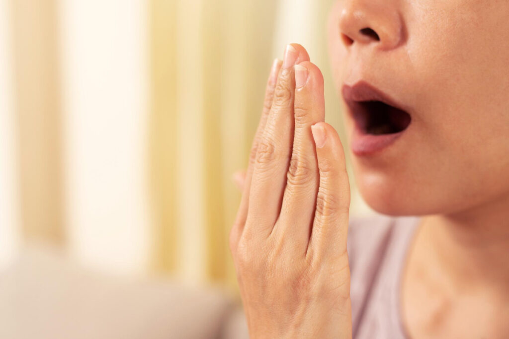 Kobieta sprawdza zapach z ust. Kserostomia - objawy suchości w ustach