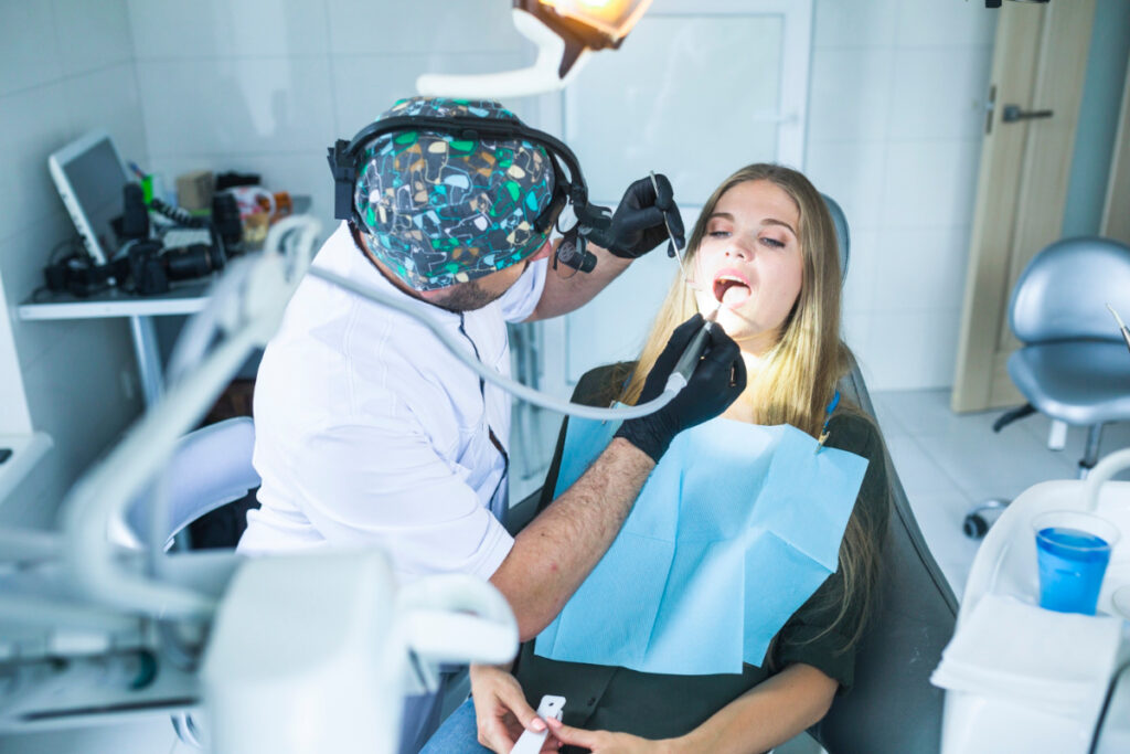 Kobieta na fotelu dentystycznym w trakcie leczenia zęba